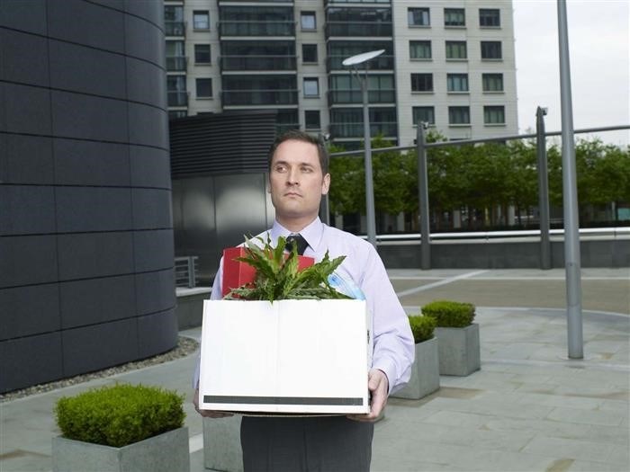 A dismissed employee leaves work with a box of belongings